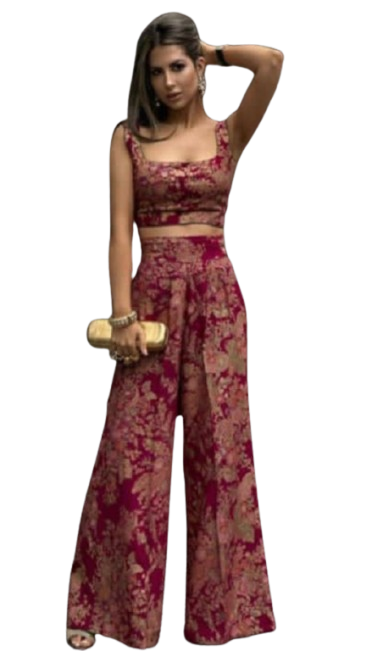 Woman in patterned two-piece outfit with wide-leg pants posing on city street.